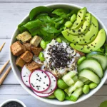 Vegan-Poke-Bowl-with-brown-rice-firm-cubed-tofu-agave-nectarmixed-greens-sliced-cucumber-sliced-avocadoedamamesliced-green-onionsliced-radish